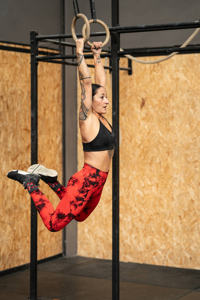 ジムでオリンピックのリングで成熟した女性アスリートトレーニングの垂直写真 - 写真・画像