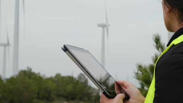 Rüzgar türbinlerini kontrol ederken telsiz ve dijital tablet kullanan kadın elektrik mühendisi - Video, Çekim