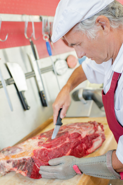Butcher skilfully preparing a cut of beef - Photo, image