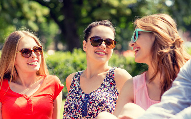 grupo de amigos sonrientes al aire libre sentado en el parque
 - Foto, Imagen