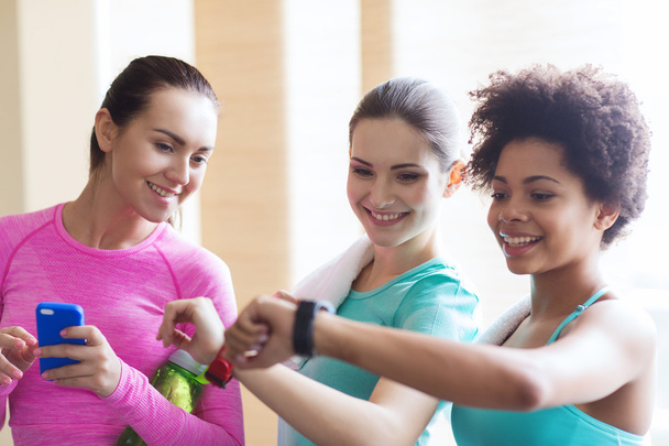happy women showing time on wrist watch in gym - Photo, image