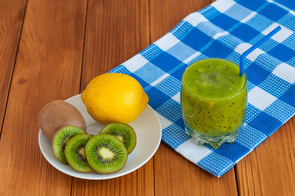 Gezonde zelfgemaakte kiwi-sap in glas en verse citroen, kiwi's op houten achtergrond. - Foto, afbeelding