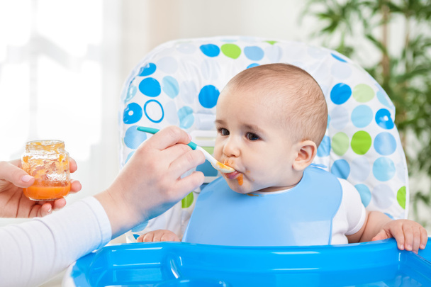 Cute hungry baby eating fruit mash - 写真・画像