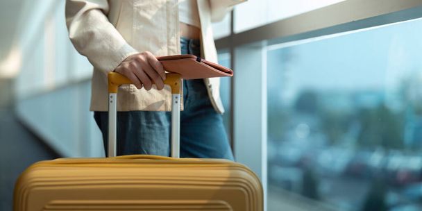 Ruka ženy cestující s pasem s letem v letištním terminálu. - Fotografie, Obrázek