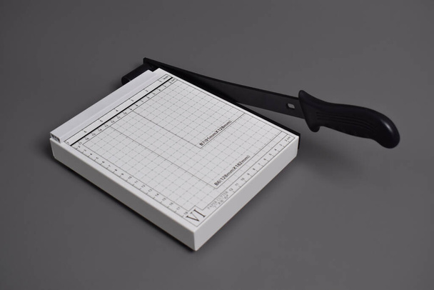 Cortador de papel blanco aislado sobre fondo gris - Foto, imagen
