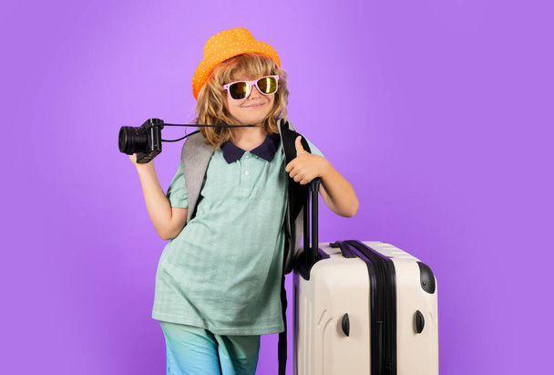 Stüdyo arka planında bavulu olan çocuk gezgin. Turist çocuk. Seyahat çantasıyla çocuk portresi. Seyahat, macera, tatil - Fotoğraf, Görsel