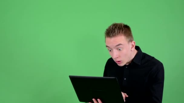 Молодой красивый мужчина работает за компьютером (ноутбуком) и радуется - зеленый экран - студия
 - Кадры, видео