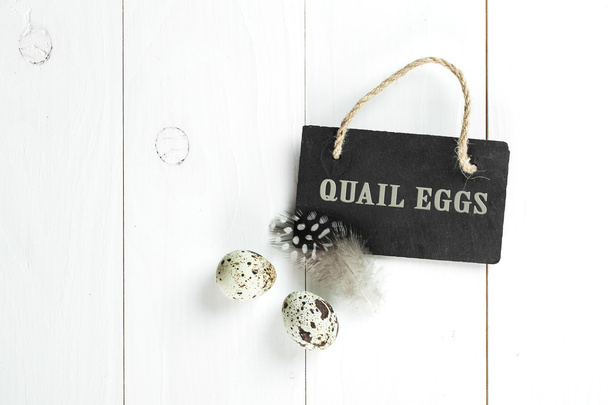 Kwartel eieren en veren met vintage schoolbord op witte houten b - Foto, afbeelding