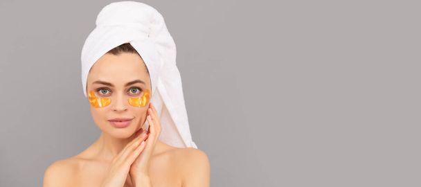 Nuori nainen frotee pyyhe käyttää kasvojen kultainen silmälappu iholle, ihonhoito. Kaunis nainen eristetty kasvot muotokuva, banneri mallintaa kopioi tilaa - Valokuva, kuva
