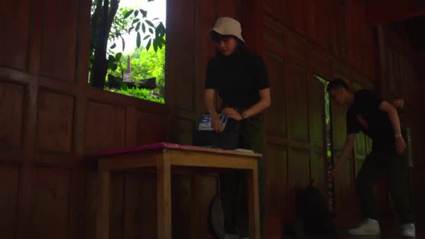 un hombre y una mujer preparándose con sus pertenencias dentro de su casa de madera en la mañana - Metraje, vídeo