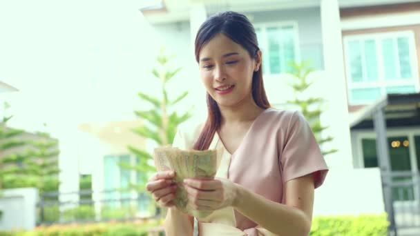 Happiness beautiful asian agent real estate businesswoman standing holding and counting cash received as success dividends as share of house sale to client money transfer housing estate broker. - Footage, Video