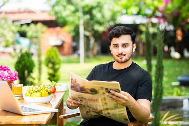 Indien jeune homme lecture journal de nouvelles en plein air - Photo, image