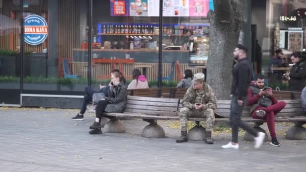 Kharkiv, Oekraïne, 27 oktober 2021. Mensen op de bank in het stadscentrum. Rustige en ontspannende levensstijl. Ik lees en spreek telefonisch. Een café. Kharkiv voor de oorlog. Hoge kwaliteit 4k beeldmateriaal - Video