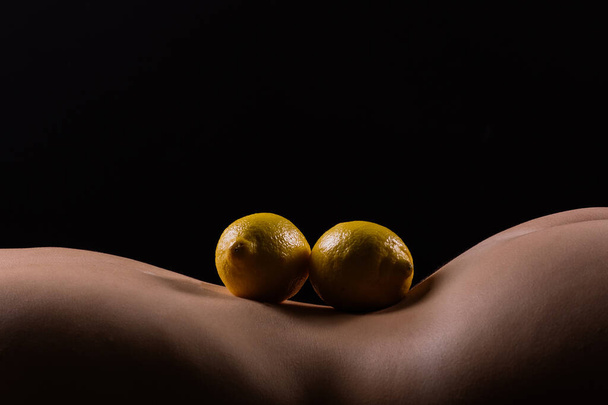 Lemon, natural vitamin c help skin whitening. Naked woman lying on back with fruit located - Foto, Imagen