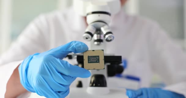 A tudós egy számítógépes chipet vizsgál mikroszkóp alatt egy laboratóriumban. Számítástechnikai fejlesztés - Felvétel, videó