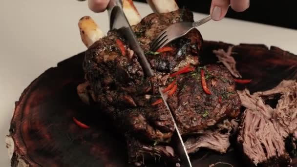 Ein Koch schneidet ein großes Stück gebackenes oder gebratenes Fleisch und demonstriert, wie saftig und zart das Fleisch geworden ist. Ein großes Stück saftiges Rindfleisch mit Knochen in Nahaufnahme - Filmmaterial, Video