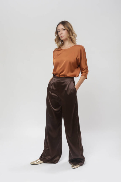 Serie studio kuvia nuori nainen malli yllään yksinkertainen kaunis asu, silkki satiini ruskea pusero ja leveä jalka housut - Valokuva, kuva