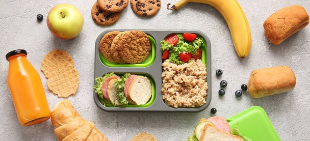 Lunchbox met verschillende smakelijke gerechten op grijze grunge achtergrond - Foto, afbeelding