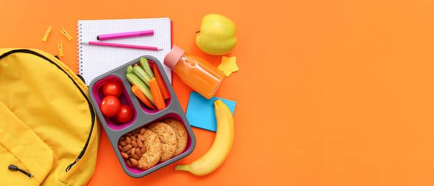 Backpack, stationery and lunch box with tasty food on orange background with space for text - Photo, Image