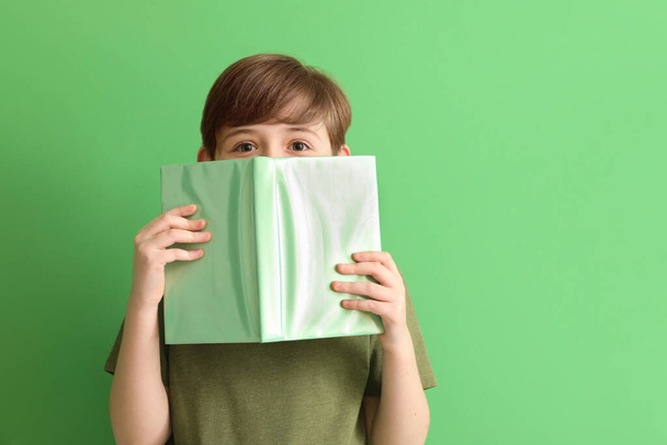 Little boy with book on green background. Children's Day celebration - Photo, Image