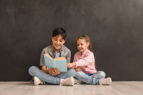 Маленькие дети читают книги возле доски - Фото, изображение