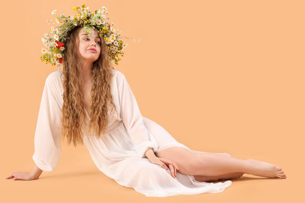 Beautiful young woman in flower wreath on beige background. Summer solstice - Photo, Image