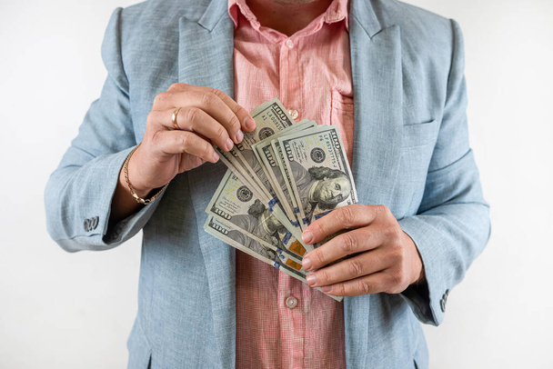  Молодой бизнесмен в костюме держит нам долларовые деньги. Финансовая концепция - Фото, изображение