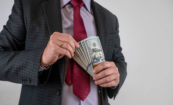 Young business worker show dollars in hand isolated on gray, finance count - Photo, Image