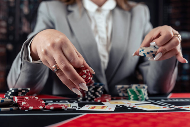 игрок женского пола играет в покер и берет фишки, чтобы поднять ставку. Казино игра - Фото, изображение