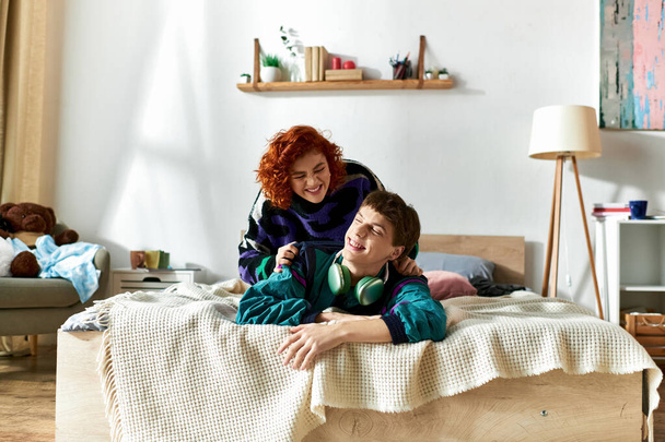 自宅で彼の魅力的な赤毛のガールフレンドとベッドに横たわっているヘッドフォンを持つ魅力的な男 - 写真・画像
