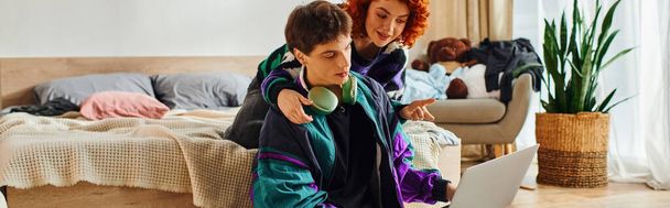 ελκυστικό ευτυχισμένο ζευγάρι σε casual ενδυμασίες περνούν χρόνο μαζί στο φορητό υπολογιστή, ενώ στο σπίτι, πανό - Φωτογραφία, εικόνα
