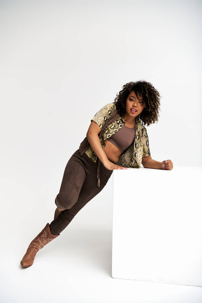 femme afro-américaine gaie avec impression animalière sur la tenue à côté du cube regardant la caméra - Photo, image