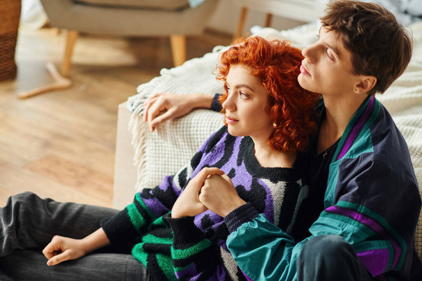 beautiful red haired woman in cozy attire hugging her handsome loving boyfriend while at home - Foto, Imagem