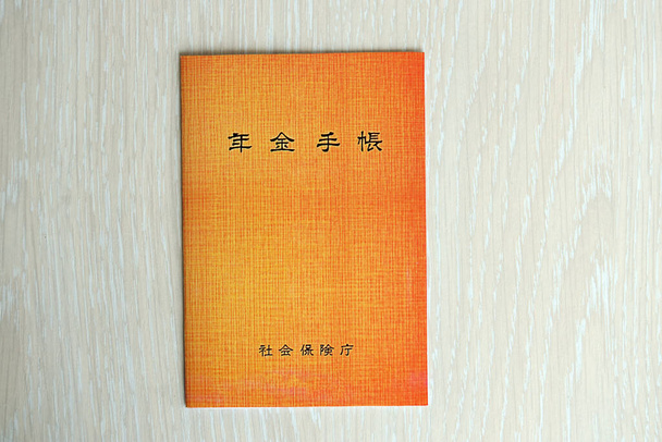 Libretto di assicurazione pensionistica giapponese sul tavolo. Libro delle pensioni arancione per i pensionati giapponesi da vicino - Foto, immagini