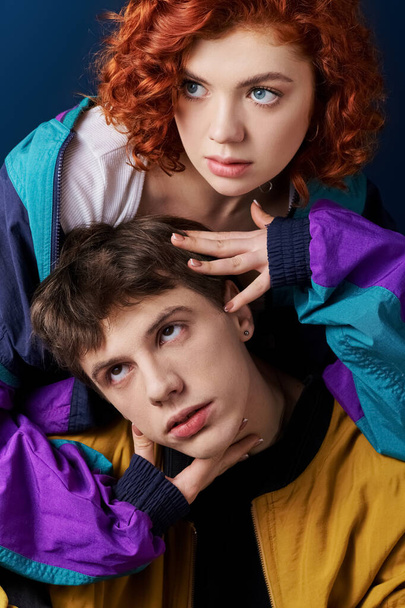 elegante pareja de moda en atuendo casual posando juntos en el fondo azul y mirando a la cámara - Foto, Imagen
