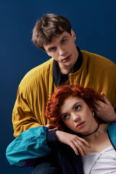 young appealing man in stylish outfit hugging his red haired girlfriend and looking at camera - Valokuva, kuva