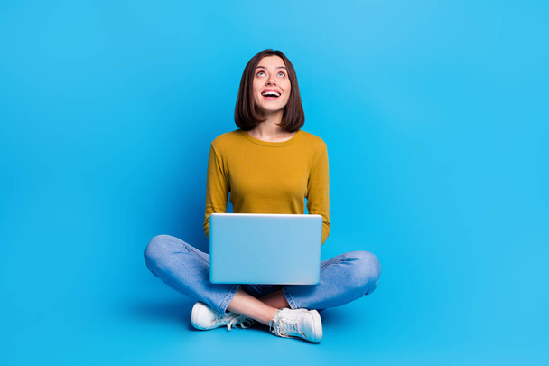 Full length photo of positive excited woman wear shirt communicating modern device looking up empty space isolated blue color background. - Φωτογραφία, εικόνα
