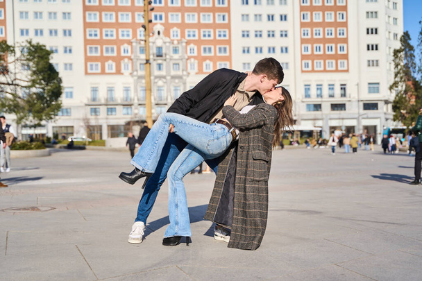 Młoda para zanurzona w namiętnym pocałunku, przekazując intensywność i romans w tętniącym życiem mieście - Zdjęcie, obraz