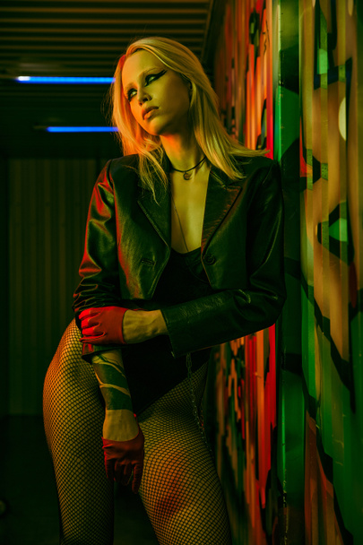 A woman wearing a leather jacket and fishnet stockings - Photo, Image