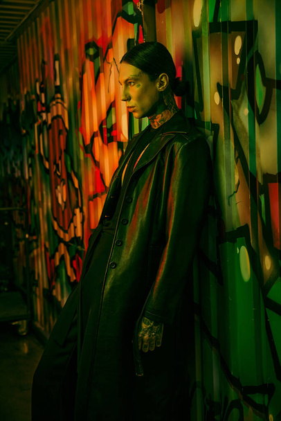 Un hombre al lado de una colorida pared cubierta de graffiti - Foto, Imagen