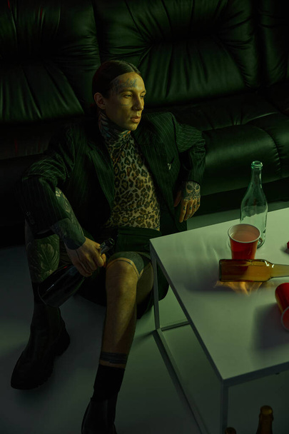 A man is seated on a couch beside a table - Photo, Image