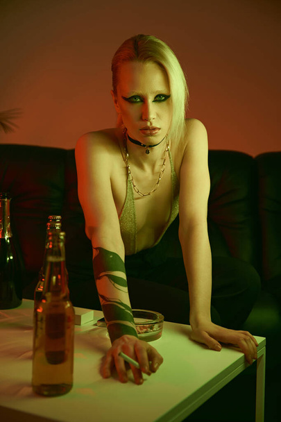Μια γυναίκα με τατουάζ ακουμπισμένη σε ένα τραπέζι. - Φωτογραφία, εικόνα