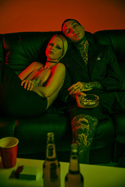 Мужчина и женщина сидят вместе на диване на вечеринке или в ночном клубе - Фото, изображение