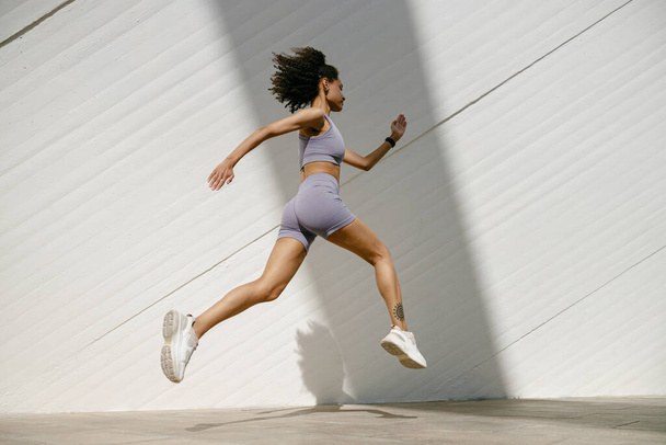 Активна жінка-спортсменка бігає вранці на сучасному будівельному тлі. Концепція здорового життя - Фото, зображення