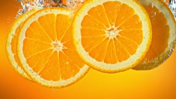 Super Slow Motion Shot frischer Orangenscheiben, die bei 1000 fps fallen und in Wasser fließen. Mit High-Speed-Kinokamera in 4K-Auflösung gefilmt. - Filmmaterial, Video