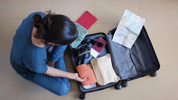 Κάτοψη του θηλυκό ταξιδιώτη συλλογή πράγματα στη βαλίτσα πριν από το ταξίδι - Πλάνα, βίντεο