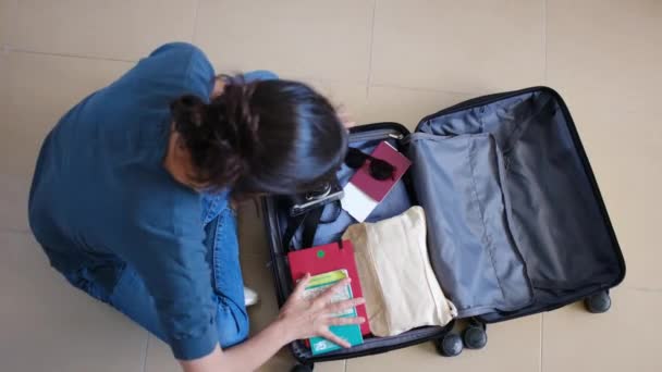 Top näkymä naispuolinen matkustaja kerätä asioita matkalaukussa ennen matkaa - Materiaali, video