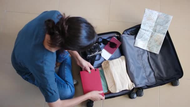 Κάτοψη του θηλυκό ταξιδιώτη συλλογή πράγματα στη βαλίτσα πριν από το ταξίδι - Πλάνα, βίντεο