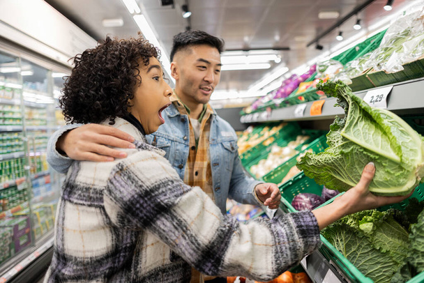 Mladý pár vyjadřuje vzrušení při sběru čerstvé zeleniny v místním obchodě s potravinami. - Fotografie, Obrázek