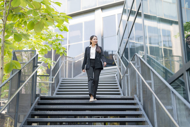 Mujer profesional de traje baja escaleras fuera de un moderno edificio de oficinas - Foto, Imagen
